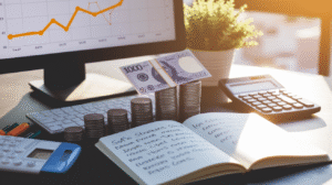 A desk with stacked coins, two 1000-denomination banknotes, an open notebook highlighting Payday Loan Strategies, a keyboard, a calculator, a potted plant, and a monitor displaying a rising line graph.