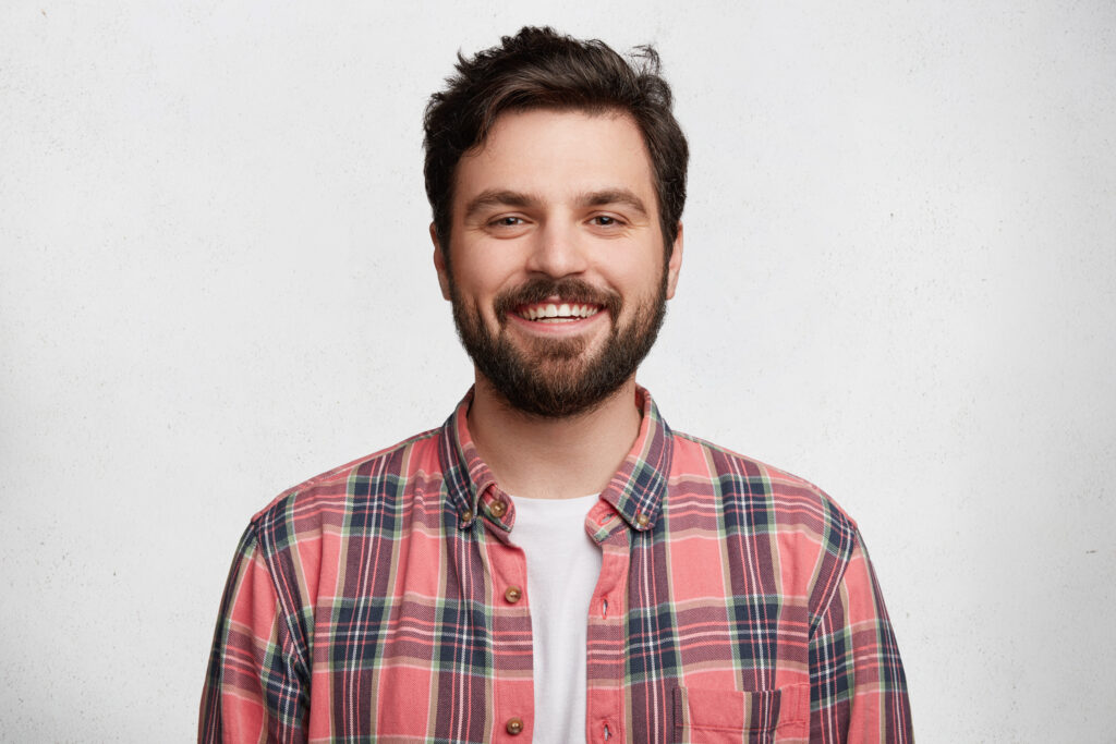Man with a beard smiling in a plaid shirt advertising payday loans against a white background.