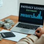 A person sits at a desk with stacks of cash, a calculator, a notepad, and a laptop displaying payday loan keywords and a bar graph. A chart is partially visible in the background.
